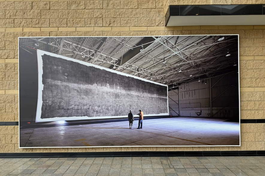 large horizontal print of two men looking at the largest photograph