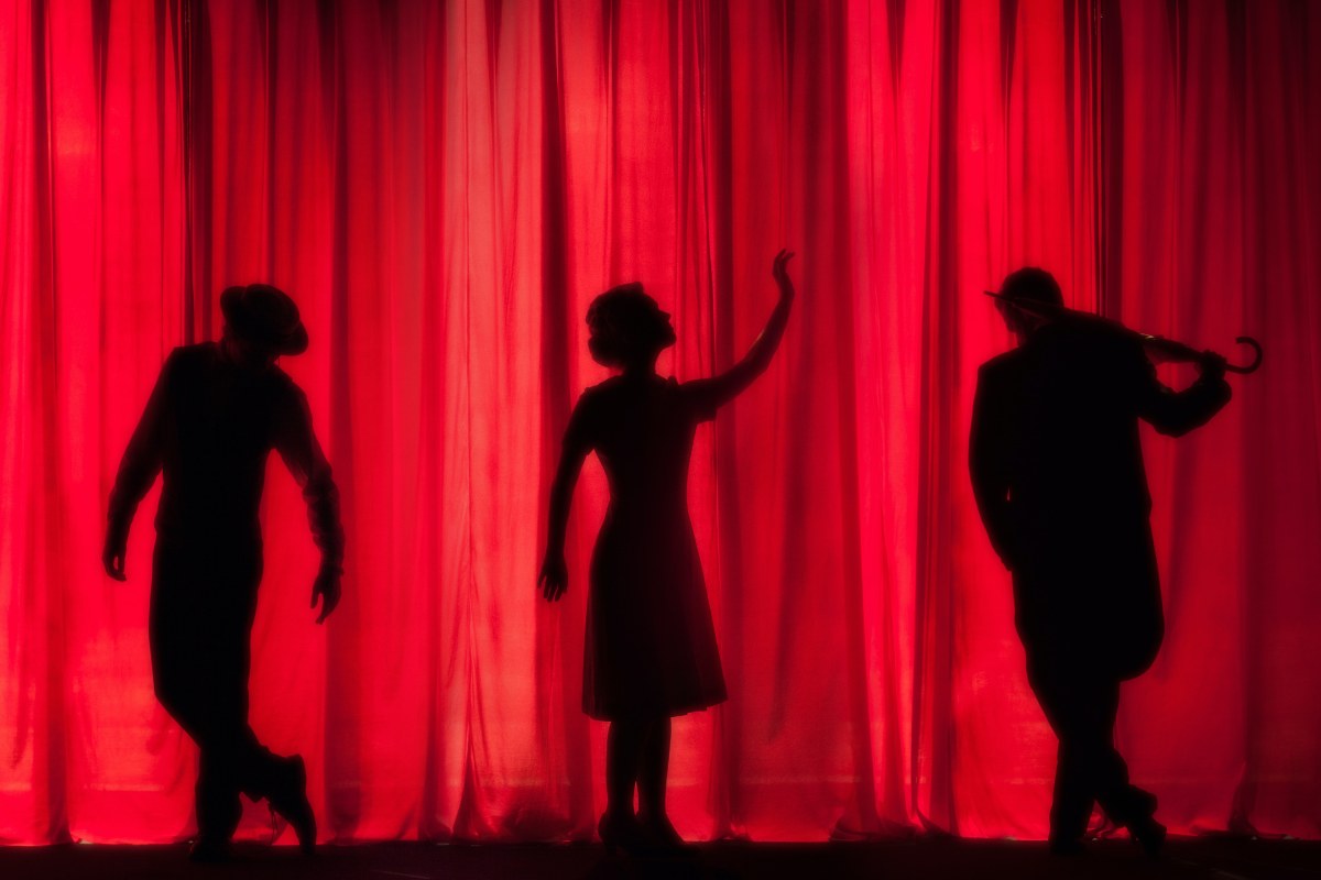 3 silhouettes against a red curtain