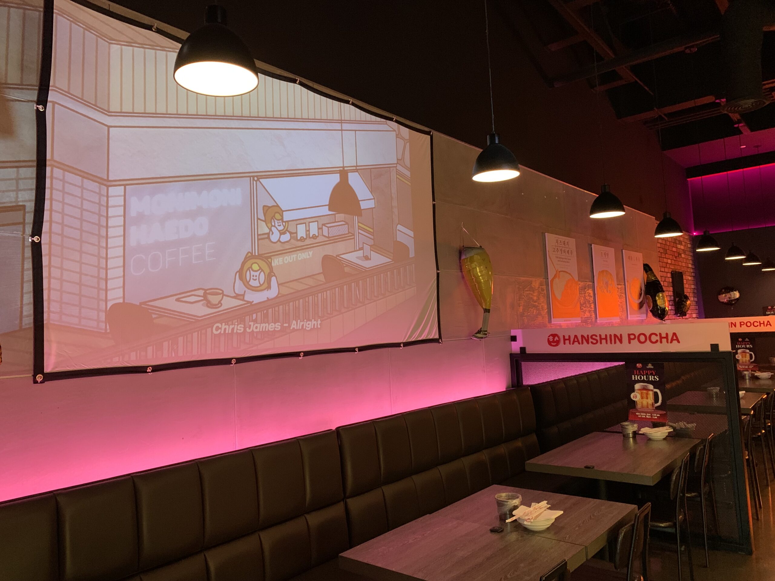 restaurant with booth seating, tables, chairs, and large screen showing cartoons