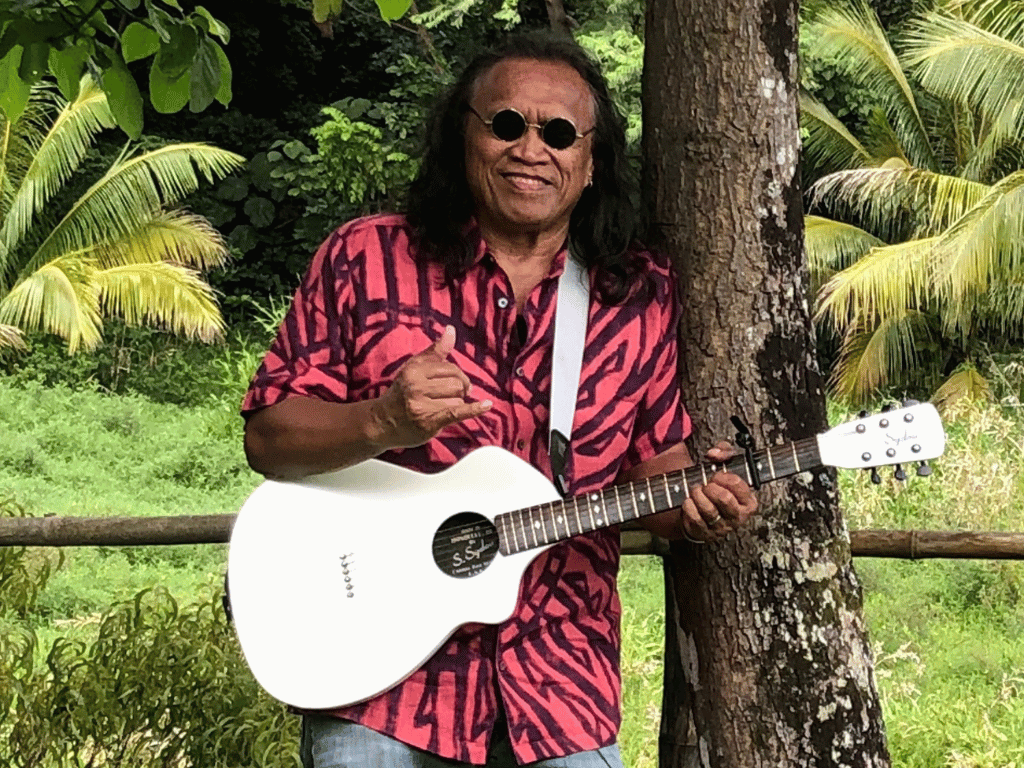 man with long black hair and sunglasses, holding a guitar
