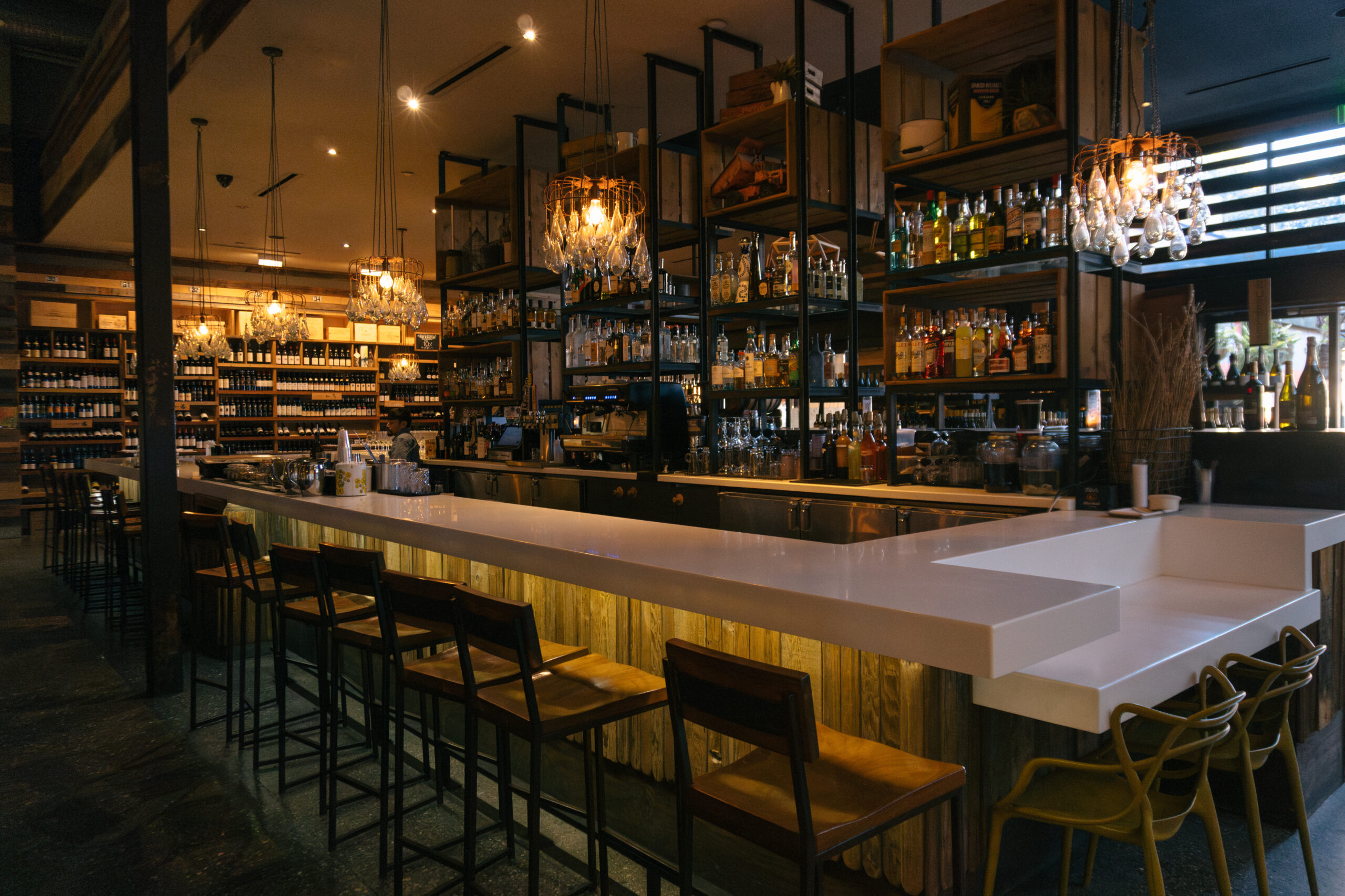 elegant, white bar area with bottles of liquor on the wall as display at Cucina Enoteca Irvine Spectrum