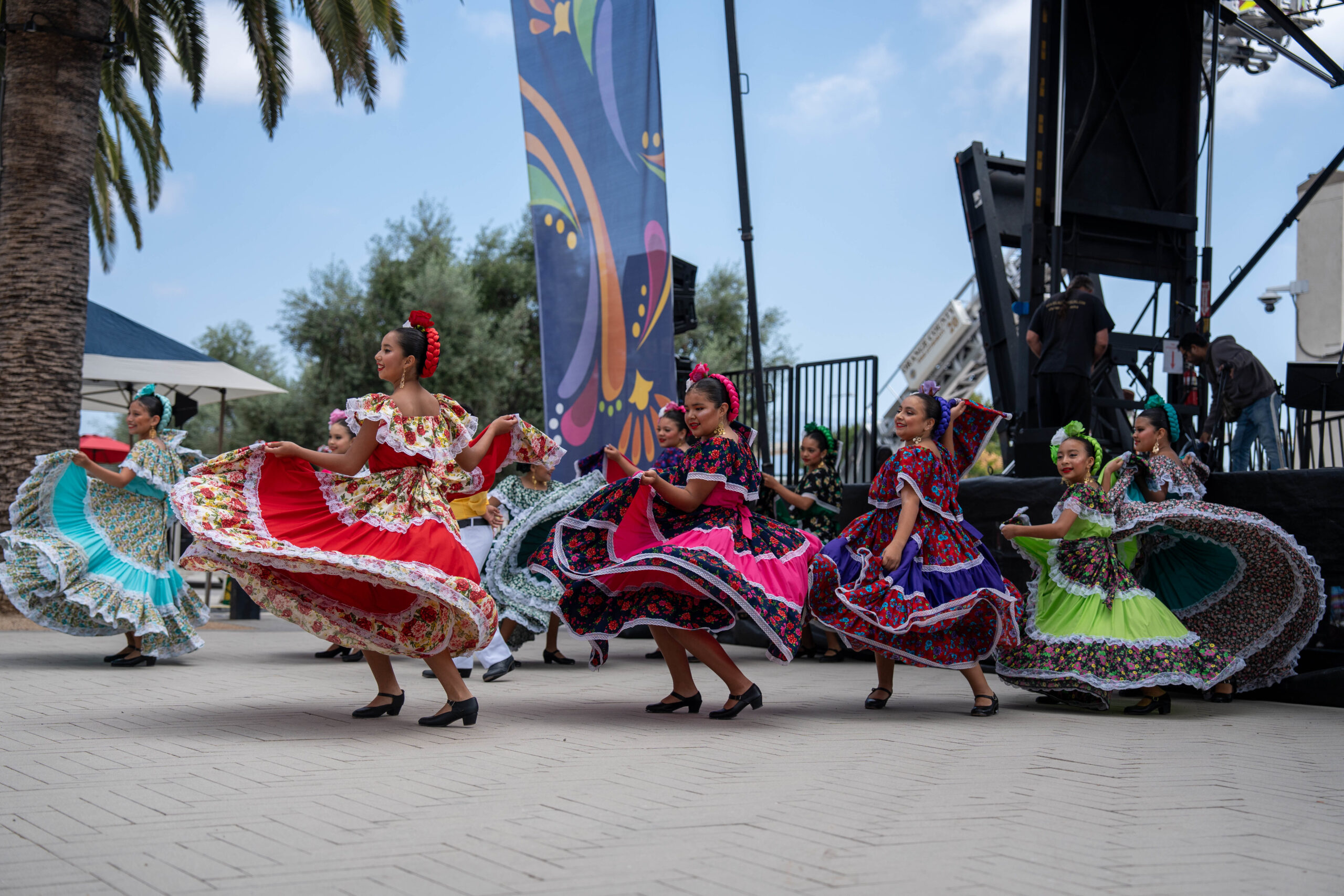 girls in colorful costumes dancing outdoors at an event