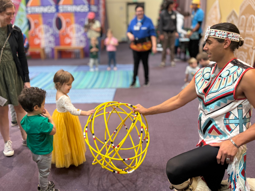 girl in yellow playing with a sphere an adult woman is holding